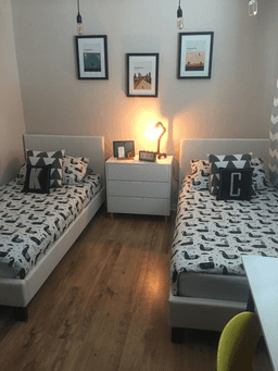 Furnished bedroom with two single beds and a bedside lamp
